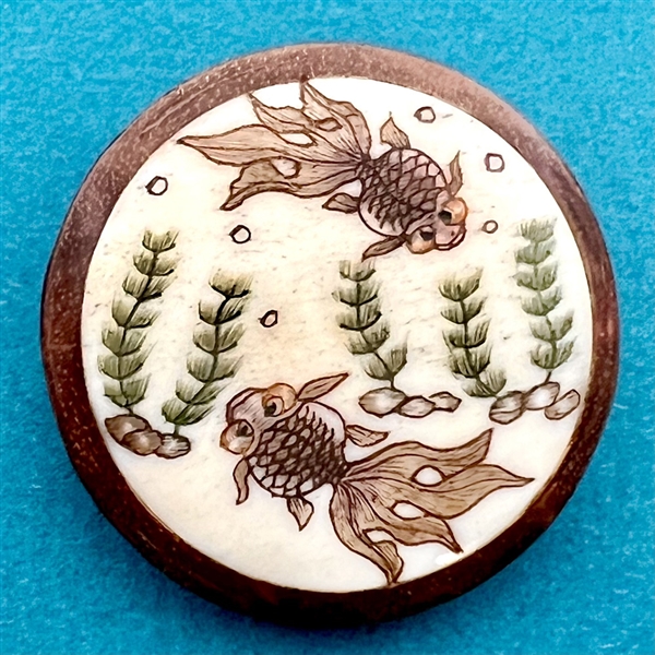 Natural material in boxwood button of two fish swimming.