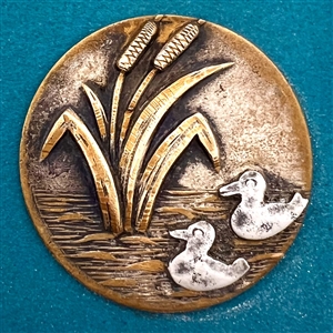 Brass button of cattails and cut steel ducks.