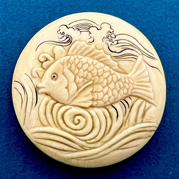 Carved natural material button of a fish swimming.