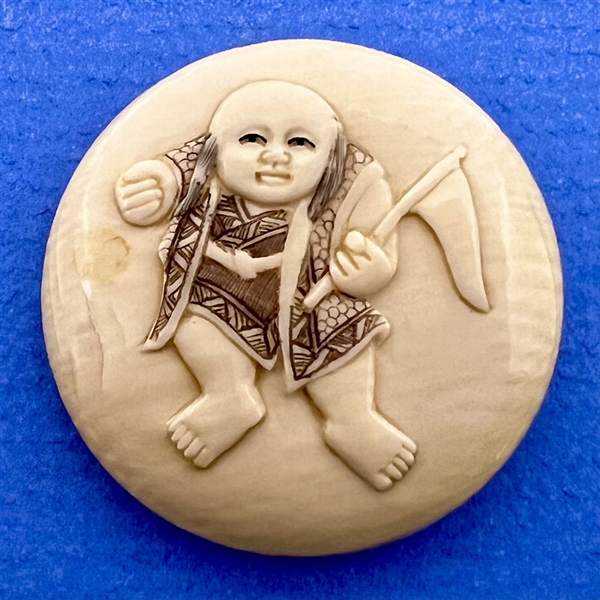 Carved natural material button of Asian boy with flag.