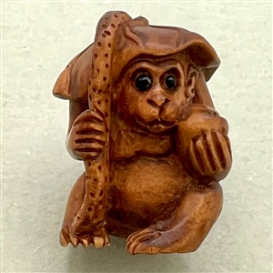 Boxwood button of a monkey under a flower hat.