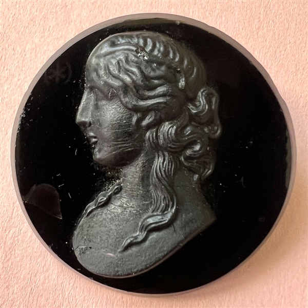 Large black glass button of a woman in profile.