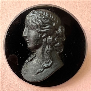 Large black glass button of a woman in profile.