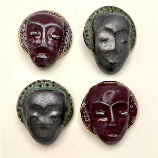 Four handmade ceramic buttons of masks or faces.