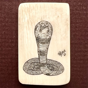 Scrimshaw on natural material button of a cobra snake.