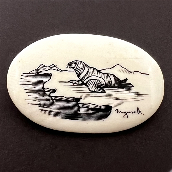 Scrimshaw button of a seal on top of ice on natural material.