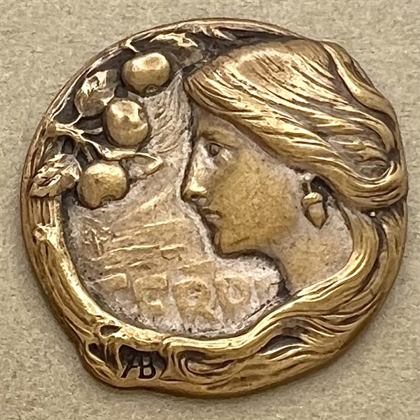 Art Nouveau brass button of a woman with verbal “Terre" (earth) by Armond Bargas.