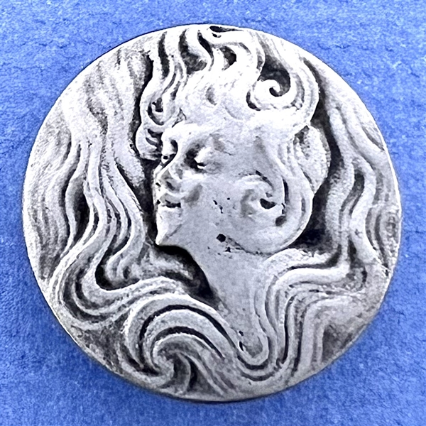 Art Nouveau style Battersea pewter button of a woman with flowing hair.