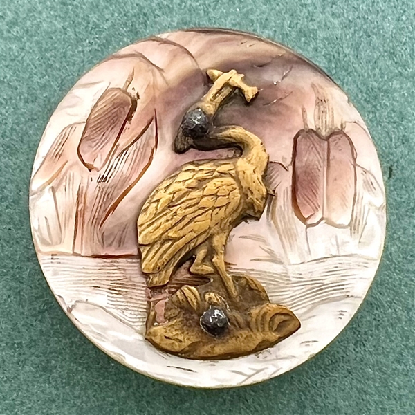 Cameo carved pearl button with cattails and brass heron with fish.