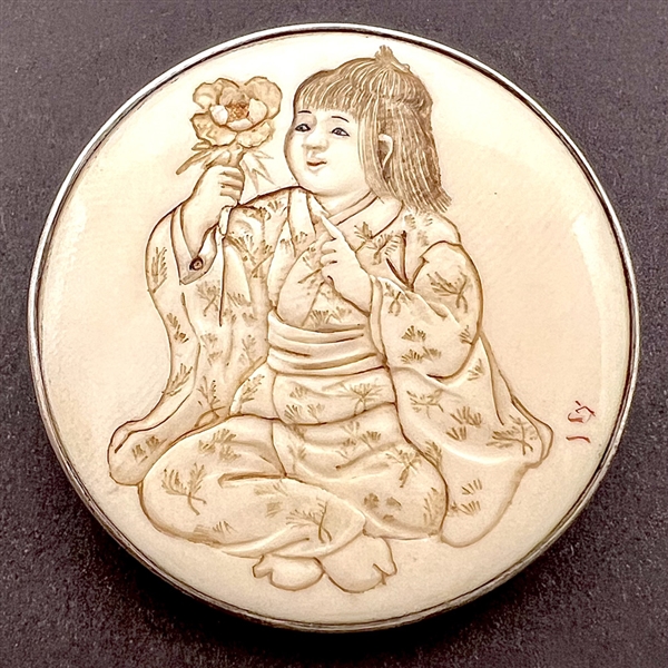 Incised, inked or painted natural material button of an Asian girl with a flower.