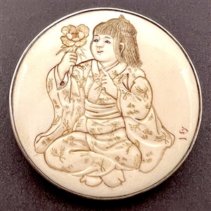 Incised, inked or painted natural material button of an Asian girl with a flower.