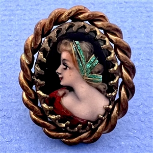 Oval enamel button with foil of a woman’s profile.