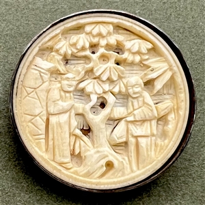 Carved natural material button of two Asian figures in a garden