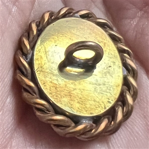 Oval enamel button with foil of a woman’s profile.