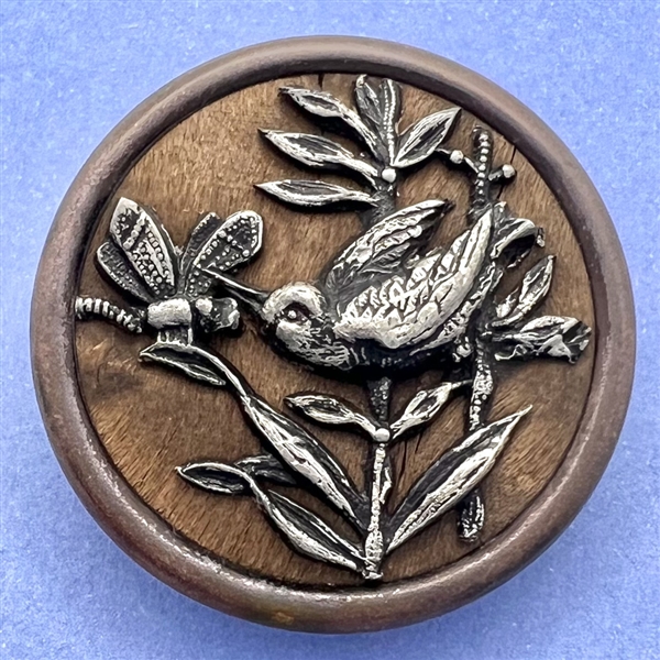 White metal bird and dragonfly over wood button. 