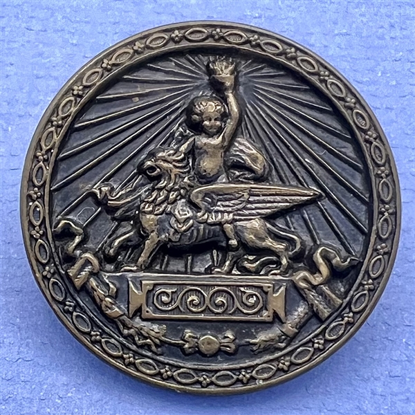 Brass button of Putti holding a torch while riding a griffin.