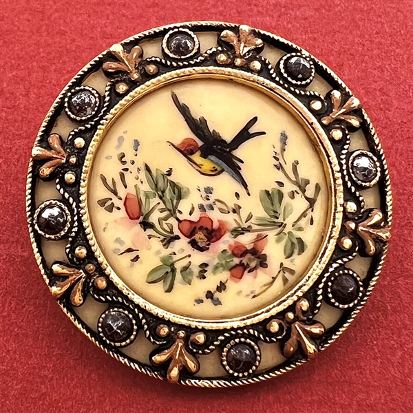 A Victorian painted bird in flight on celluloid set in metal with cut steels button.