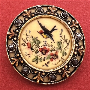 A Victorian painted bird in flight on celluloid set in metal with cut steels button.