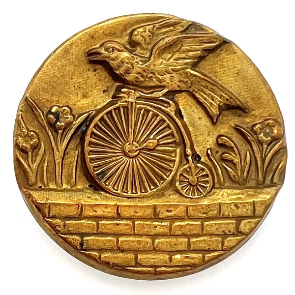 Rare brass button of a parrot riding a penny farthing bicycle.