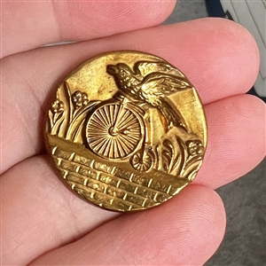 Rare brass button of a parrot riding a penny farthing bicycle.