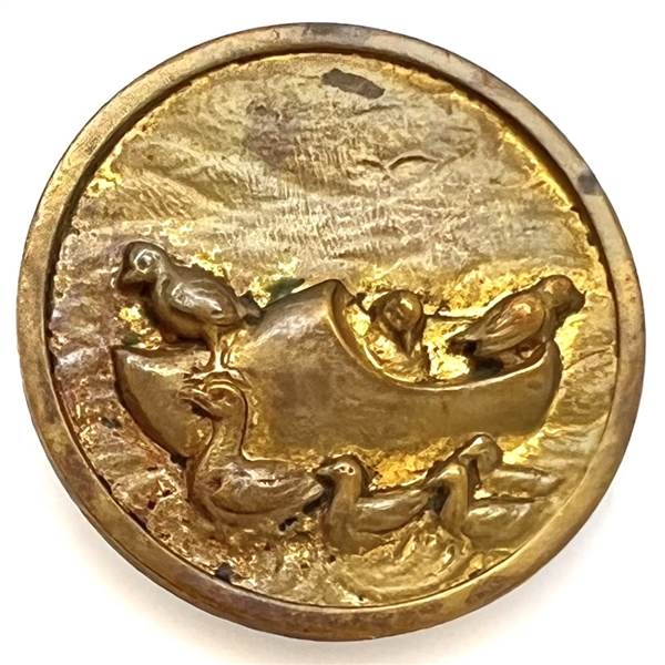 Brass button of ducks riding in a wooden clog boat.