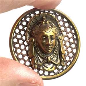 Brass screen back button of a royal woman's head.