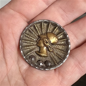 Steel cup button of a Greek woman's head.