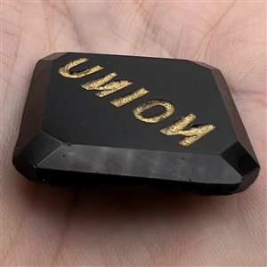 Modified square black glass verbal button of the word “Union with the N's reversed.