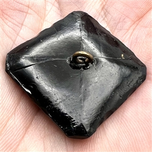 Modified square black glass verbal button of the word “Union with the N's reversed.