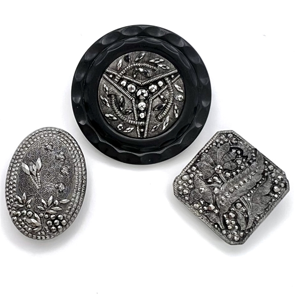 Three black glass buttons with silver luster.