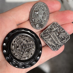 Three black glass buttons with silver luster.