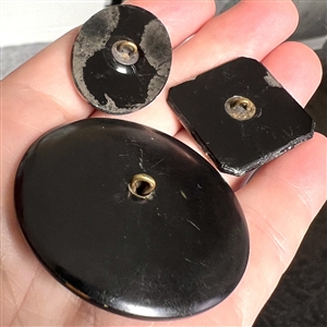 Three black glass buttons with silver luster.