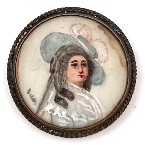 Painting on natural material button of woman in blue hat.