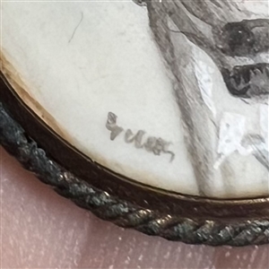 Painting on natural material button of woman in blue hat.