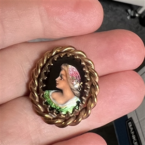 Oval enamel button with foil of a woman's profile.