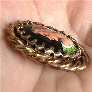 Oval enamel button with foil of a woman's profile.