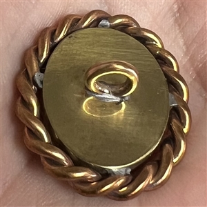 Oval enamel button with foil of a woman's profile.