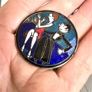 A champlevé enamel button of a 1920's man and woman out on the town.