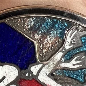 A champlevé enamel button of a 1920's man and woman out on the town.