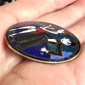 A champlevé enamel button of a 1920's man and woman out on the town.