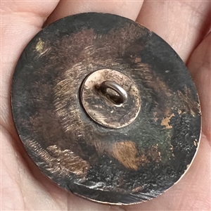 A champlevé enamel button of a 1920's man and woman out on the town.
