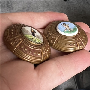 Two painted porcelain buttons set in brass.