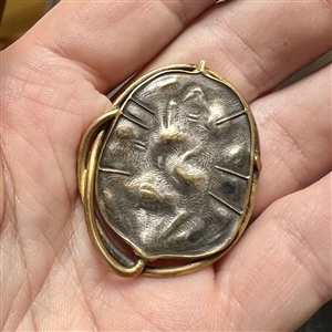 Arts and Crafts metal button of a stylized leaf.