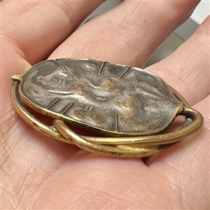 Arts and Crafts metal button of a stylized leaf.