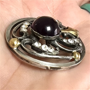 Arts and Crafts button of gilded and silvered metal with amethyst glass center.