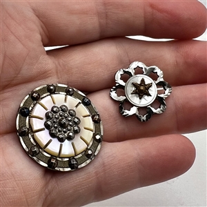 Two steel and pearl buttons.