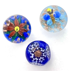 Three glass paperweight studio buttons with gold stone accents.