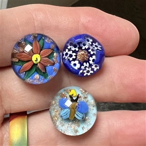 Three glass paperweight studio buttons with gold stone accents.