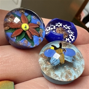 Three glass paperweight studio buttons with gold stone accents.