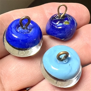Three glass paperweight studio buttons with gold stone accents.
